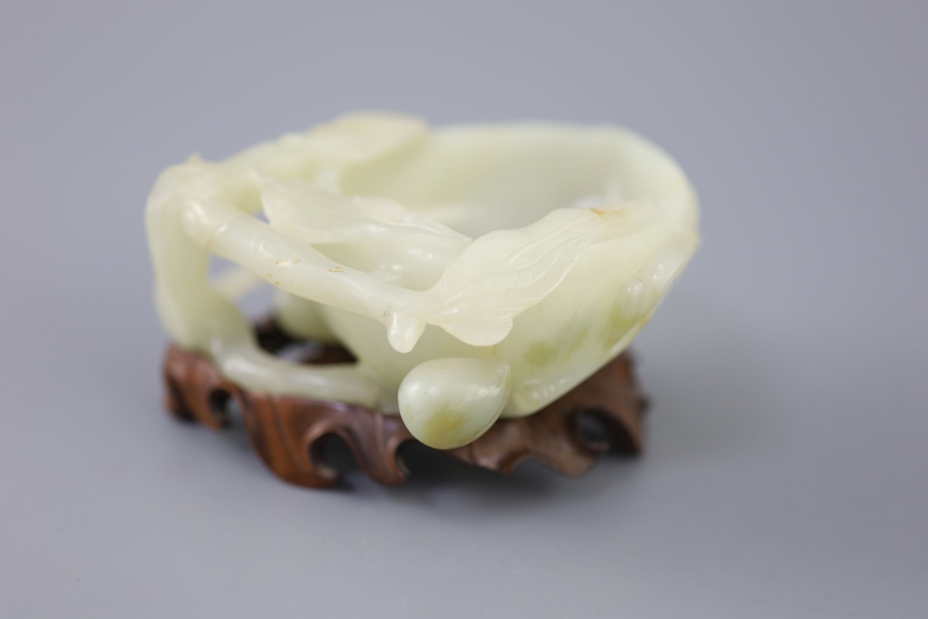 A Chinese pale celadon jade peach brush washer, 17th/18th century 11.3cm at widest point, wood stand
